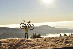 Cyclist holding a road bike above a mountain landscape