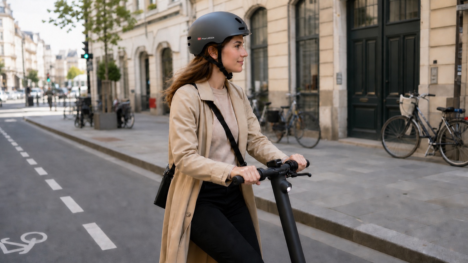 Woman riding an electric scooter with a small Maya LARSEN name and Danish flag sticker on her helmet