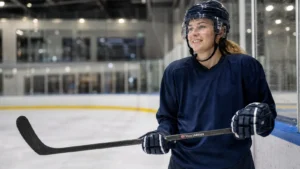 Female ice hockey player holding a stick with a small personalised name and Norwegian flag sticker